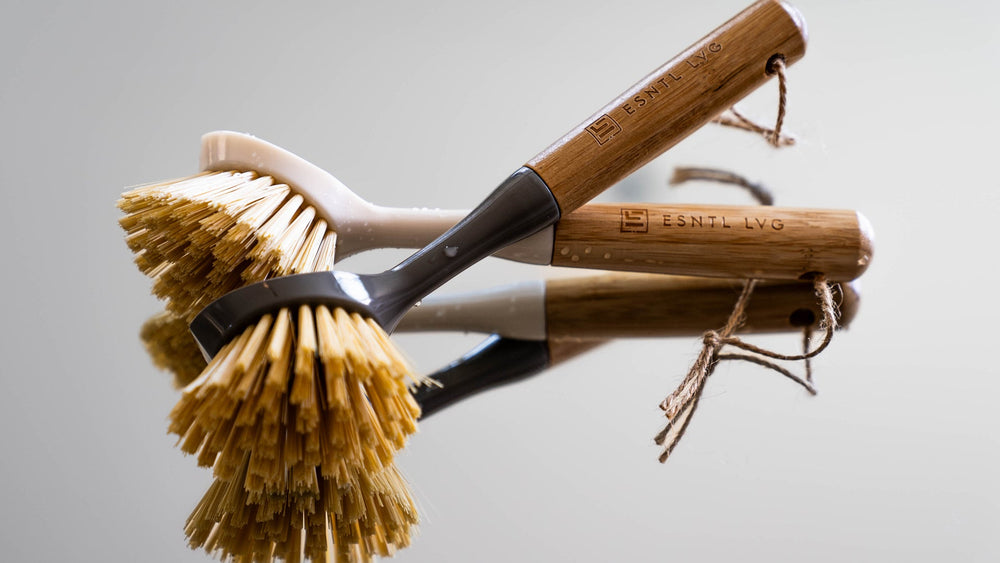 Close-up of ESNTL LVG sustainable cleaning brushes with bamboo handles and natural bristles, highlighting eco-friendly and reusable home cleaning solutions.