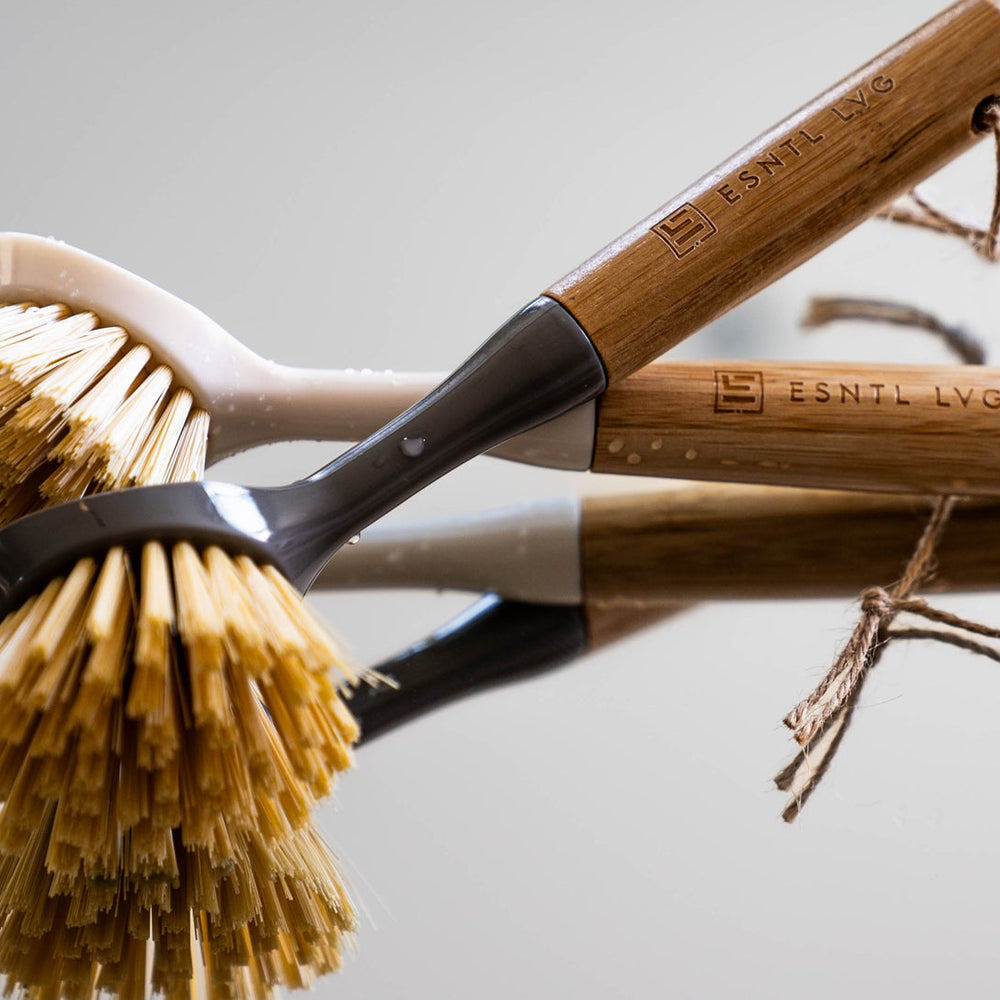 Close-up of ESNTL LVG sustainable cleaning brushes with bamboo handles and natural bristles, highlighting eco-friendly and reusable home cleaning solutions.